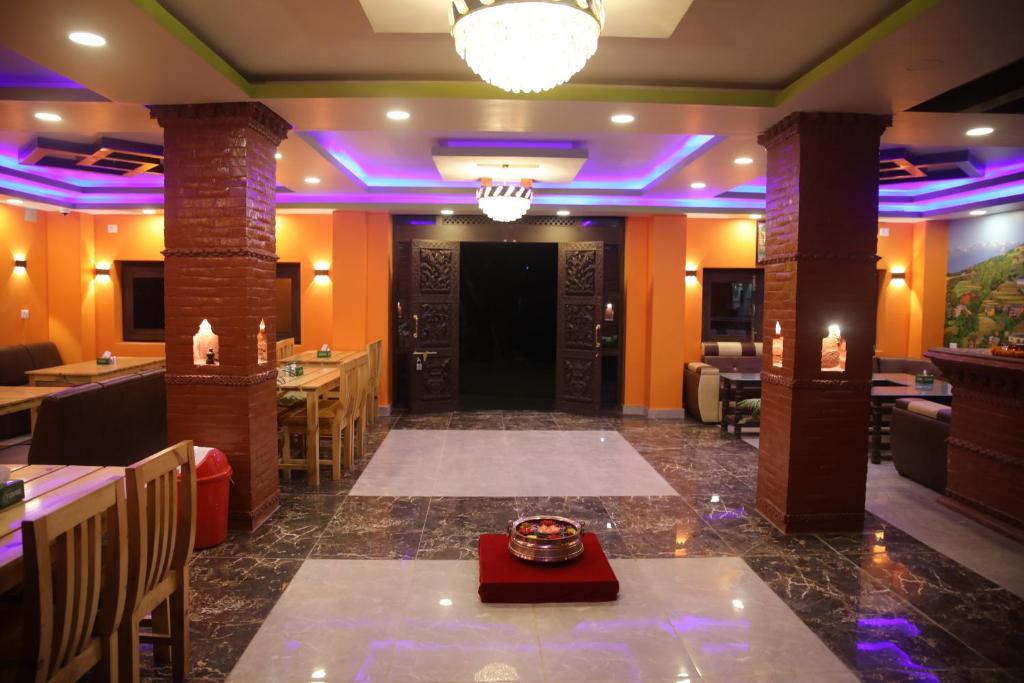 un restaurante con iluminación púrpura, mesas y sillas en The Red House Bandipur, en Bandipur