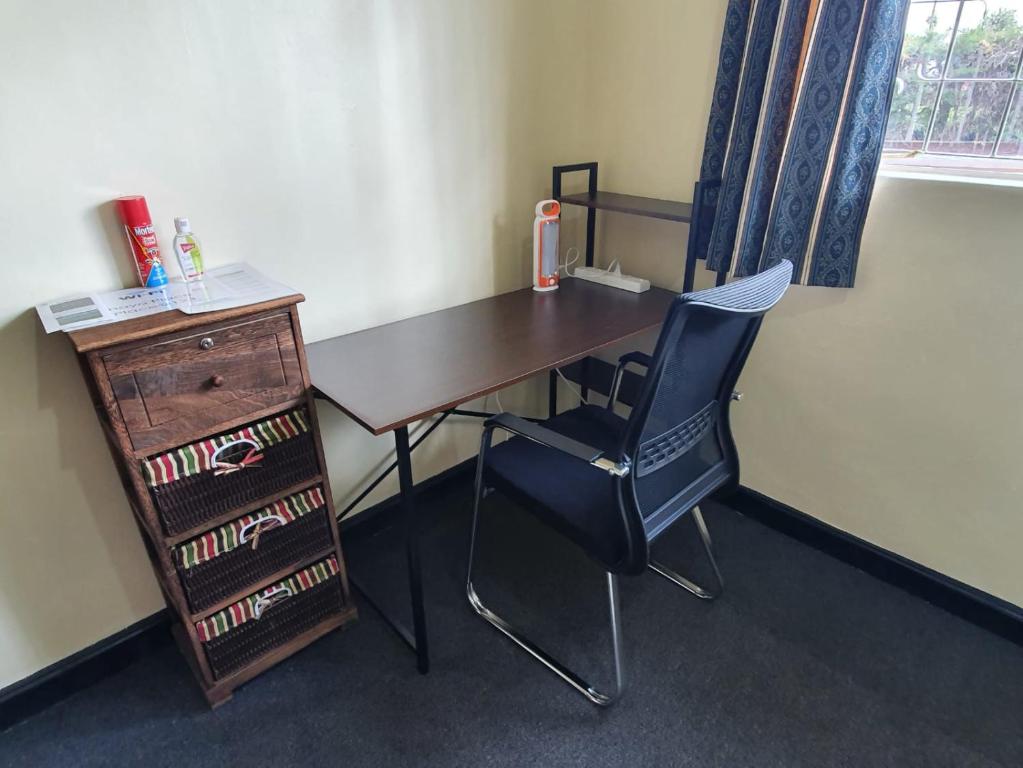 a desk with a chair and a wooden desk with a drawer at Thayo Place in Nyeri