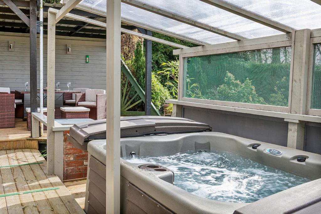 a hot tub on a patio with a pergola at Finest Retreats - Garden Lodge in Craven Arms
