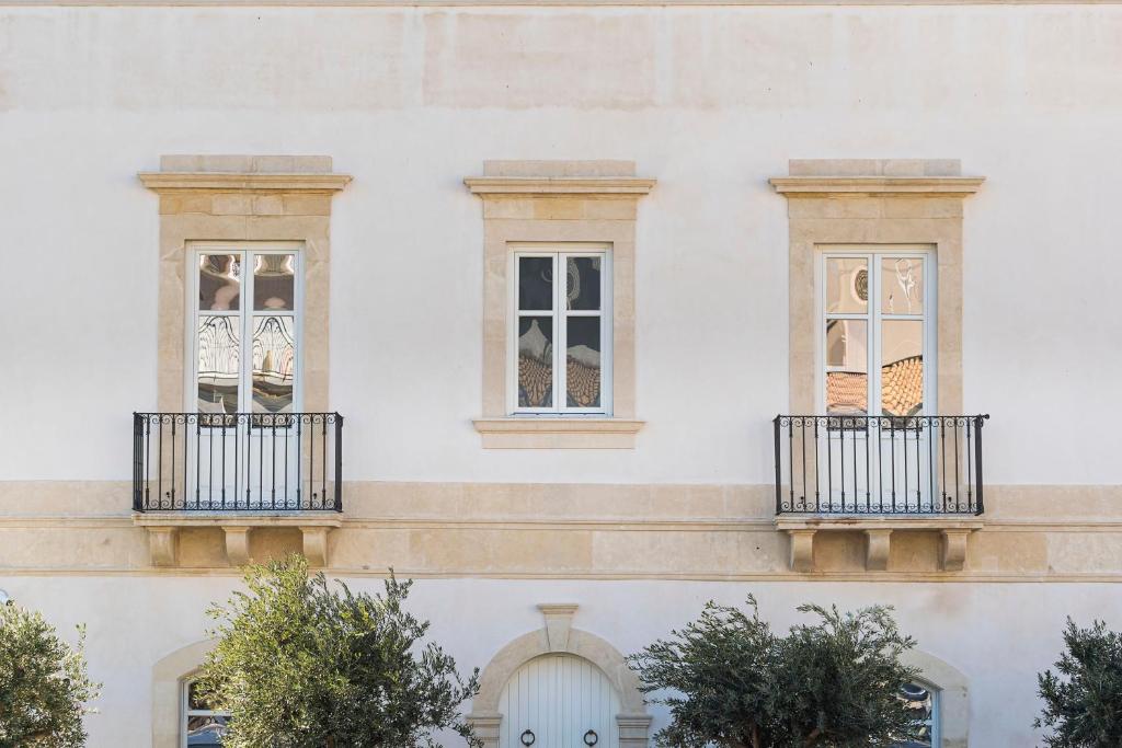 un edificio bianco con tre finestre sopra di Byssus Suites a Siracusa