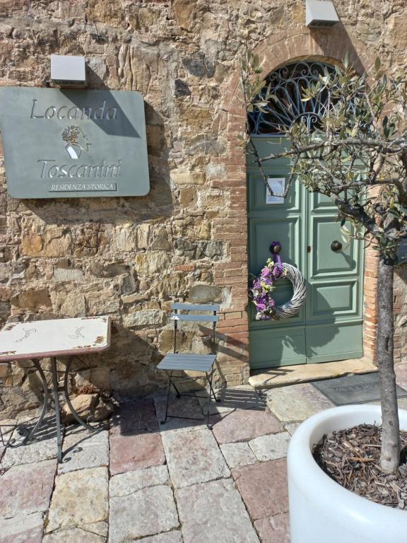 een groene deur met een bord op een stenen muur bij B&B Locanda Toscanini in Cetona