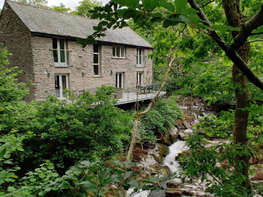 una casa de piedra con un puente sobre un arroyo en The Old Water Mill, en Kendal