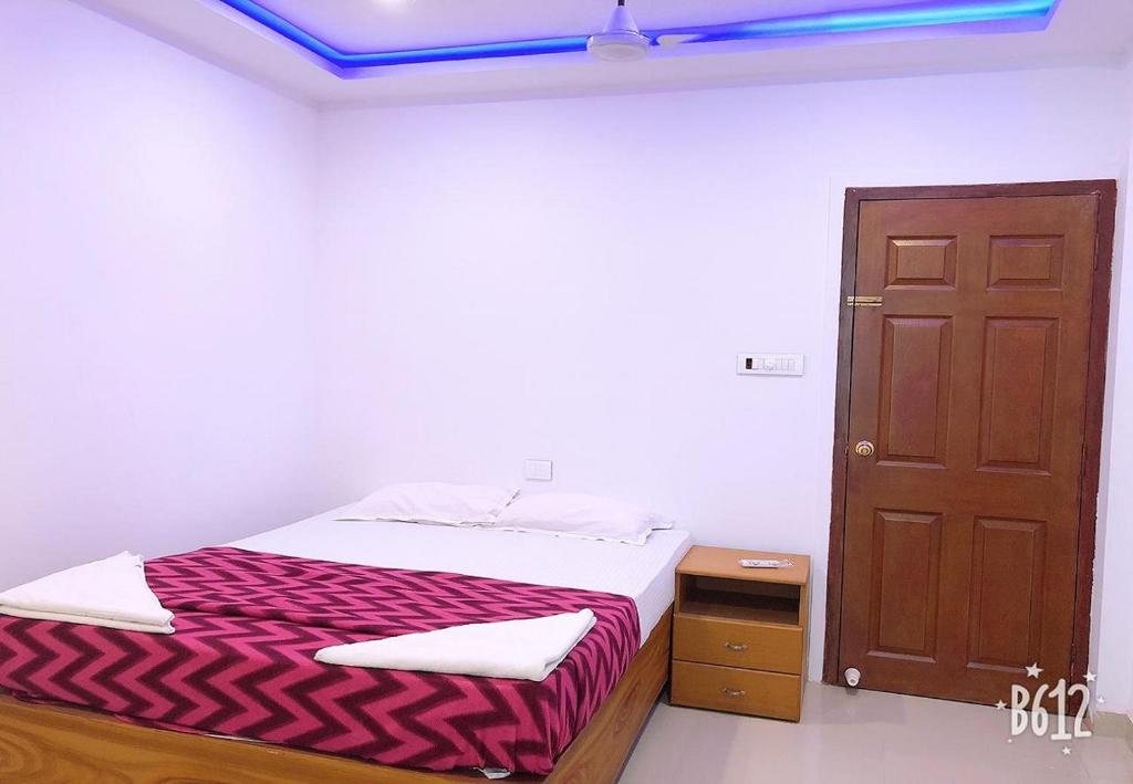 1 dormitorio con cama y puerta marrón en Phils' Residency & Banquets, en Kochi