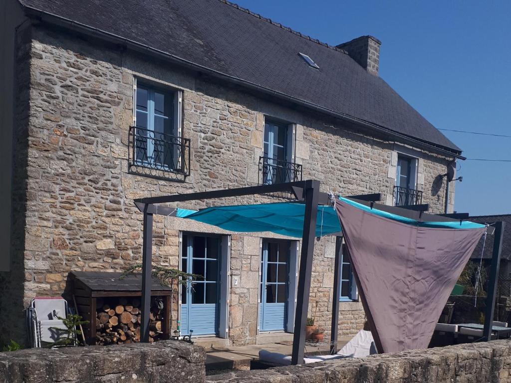 een stenen huis met een blauwe paraplu en een grill bij Gite Bleu Brittany near Dinan in Plumaudan