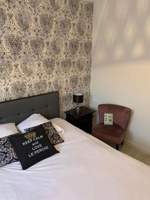 a bedroom with a white bed and a chair at LOGIS-Hôtel Restaurant Auberge Les Vallées Du Perche in Vichères