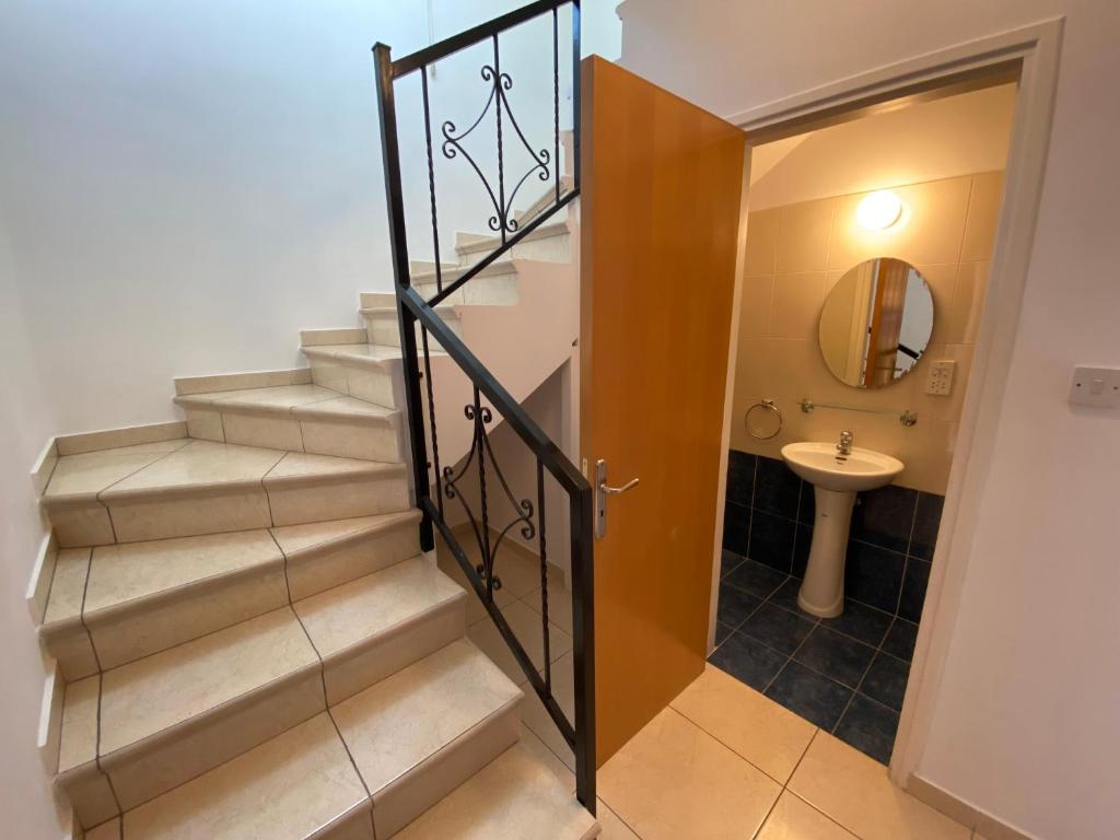 baño con escaleras, lavabo y espejo en Three Bedroom Casa de Paphos, en Pafos