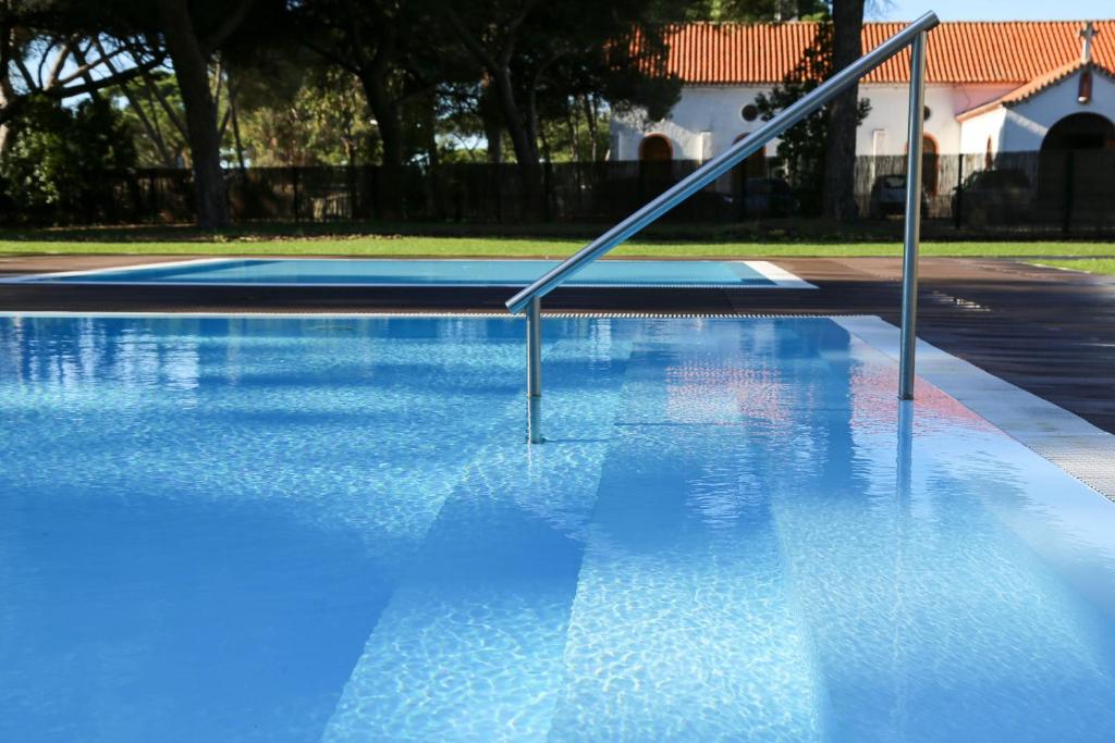 a blue swimming pool with a metal hand rail at INATEL Caparica in Costa da Caparica