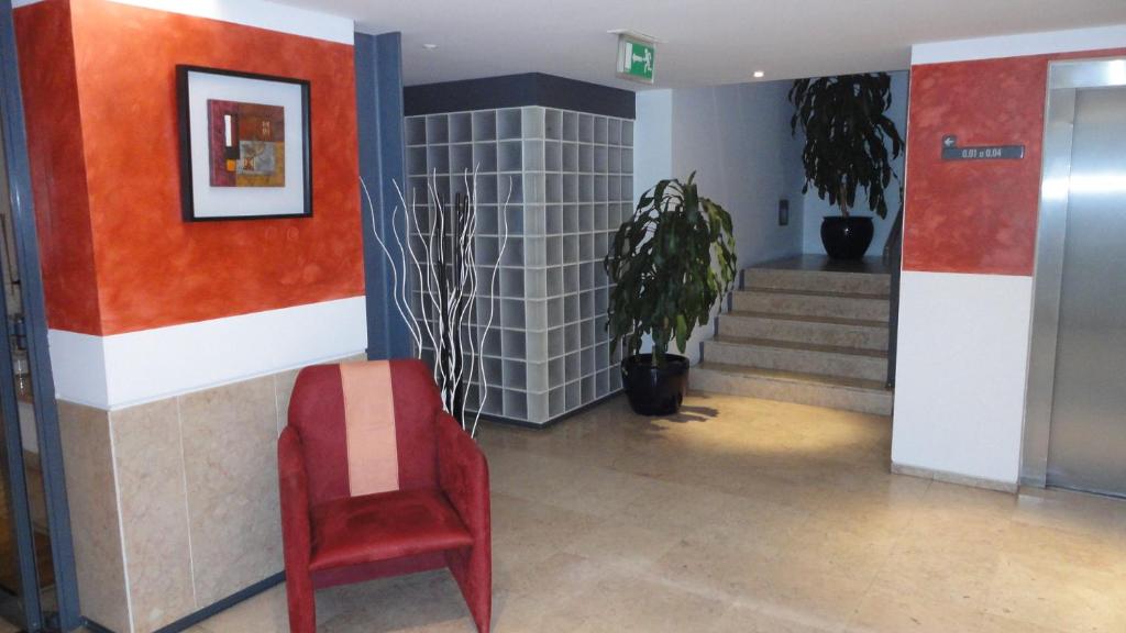 a red chair sitting in a hallway with stairs at INATEL Caparica in Costa da Caparica
