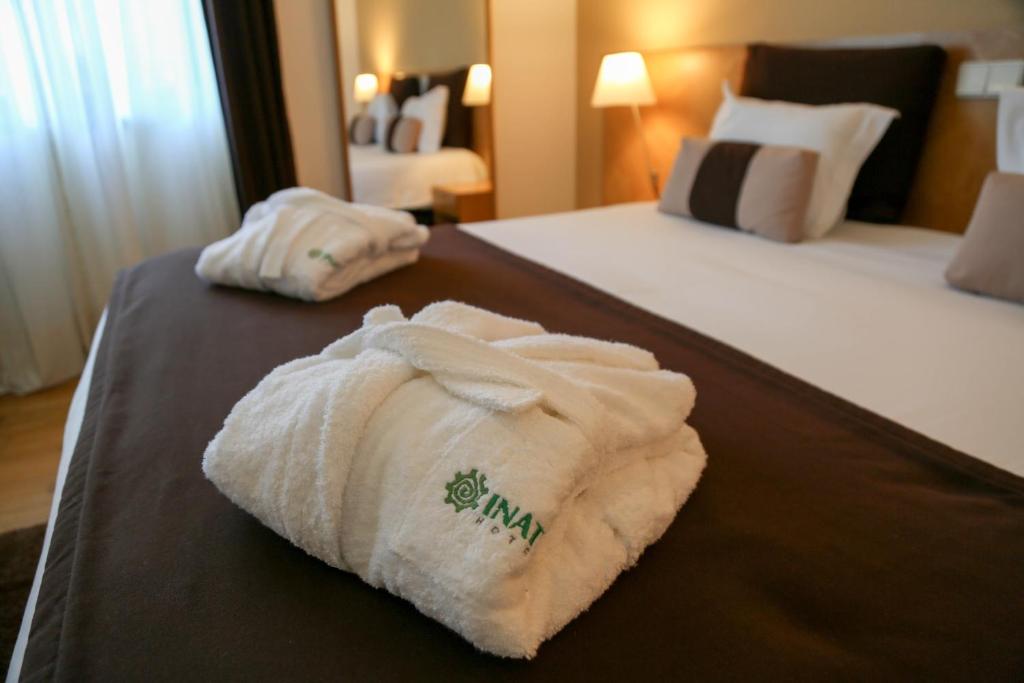two towels on a bed in a hotel room at INATEL Caparica in Costa da Caparica