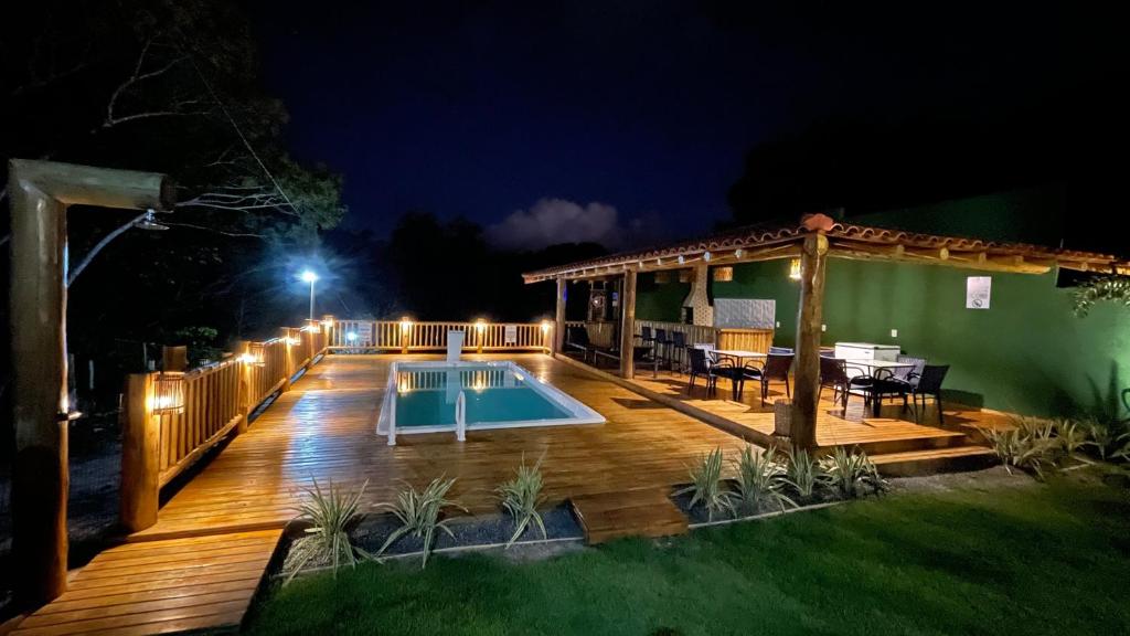 a deck with a pool and a pergola at night at Encanto do mar residencial in Caraíva