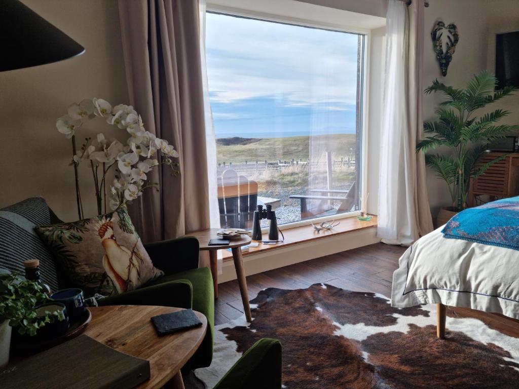 a bedroom with a large window with a view of the ocean at Abhaig Boutique B&B - Small & luxurious in a great location! in Uig