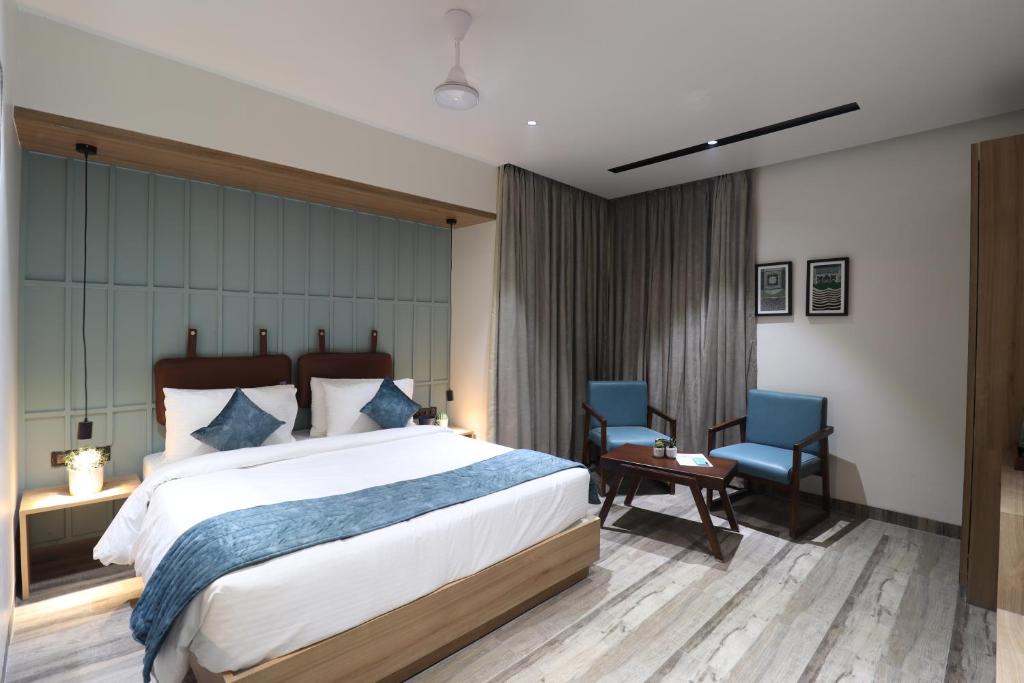 a bedroom with a large bed and two blue chairs at Hotel Chitra Executive in Solapur