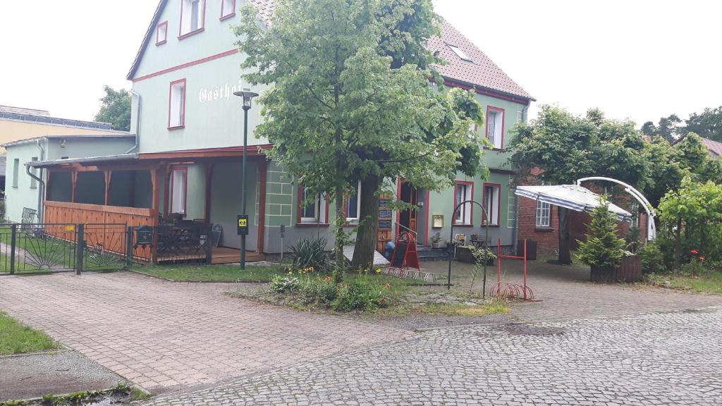 una casa con un árbol y un patio de juegos delante de él en Gasthof Alte Fischerhütte, en Altfriesack