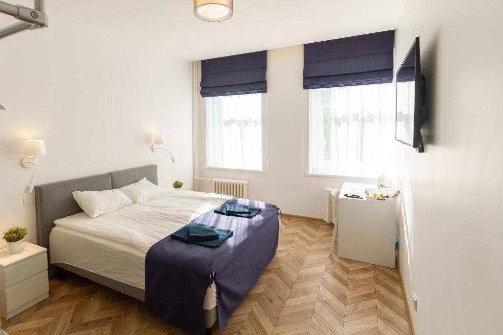 a bedroom with a bed and two windows at HOT SPOT Vilnius Apartments! in Vilnius