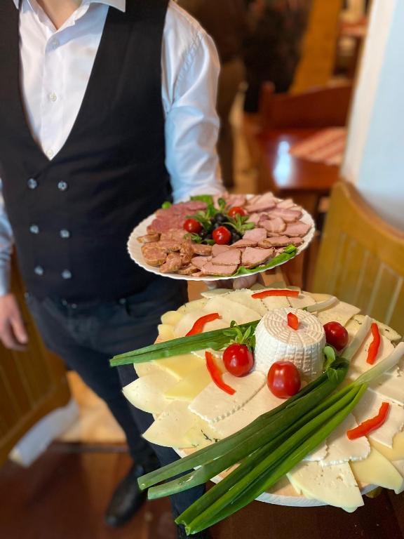 a person holding two plates of food on a table at Pensiunea LUKA Slanic Moldova in Slănic-Moldova