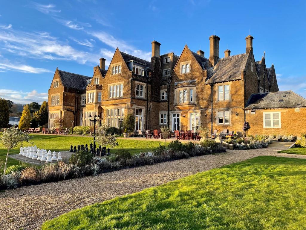 un vieux château avec une pelouse devant lui dans l'établissement Hartsfield Manor, à Dorking