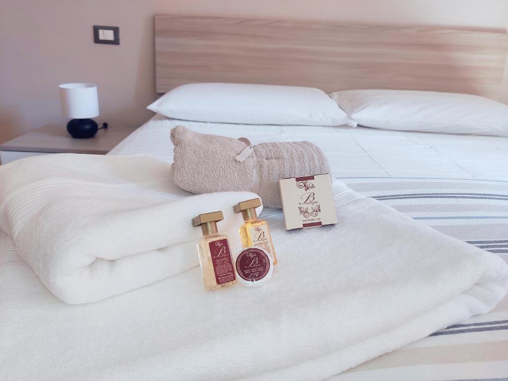 1 cama con sábanas blancas y 2 botellas de jabón en BeHome Apartment Holidays en Bolonia