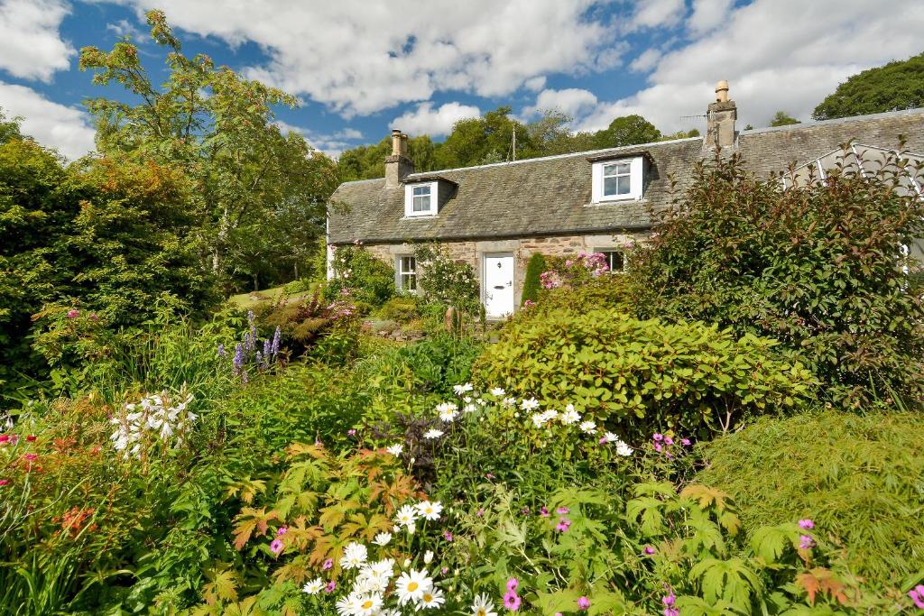 uma casa velha no meio de um jardim com flores em Wintergreen em Pitlochry