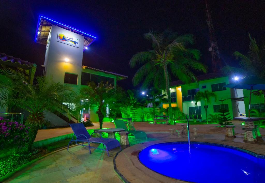 a swimming pool at night with chairs and a table at Pousada Kalunga in Flecheiras