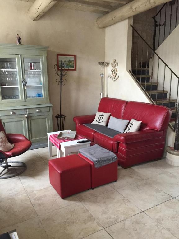 a red couch and stool in a living room at Maison au bord de mer in Saintes-Maries-de-la-Mer