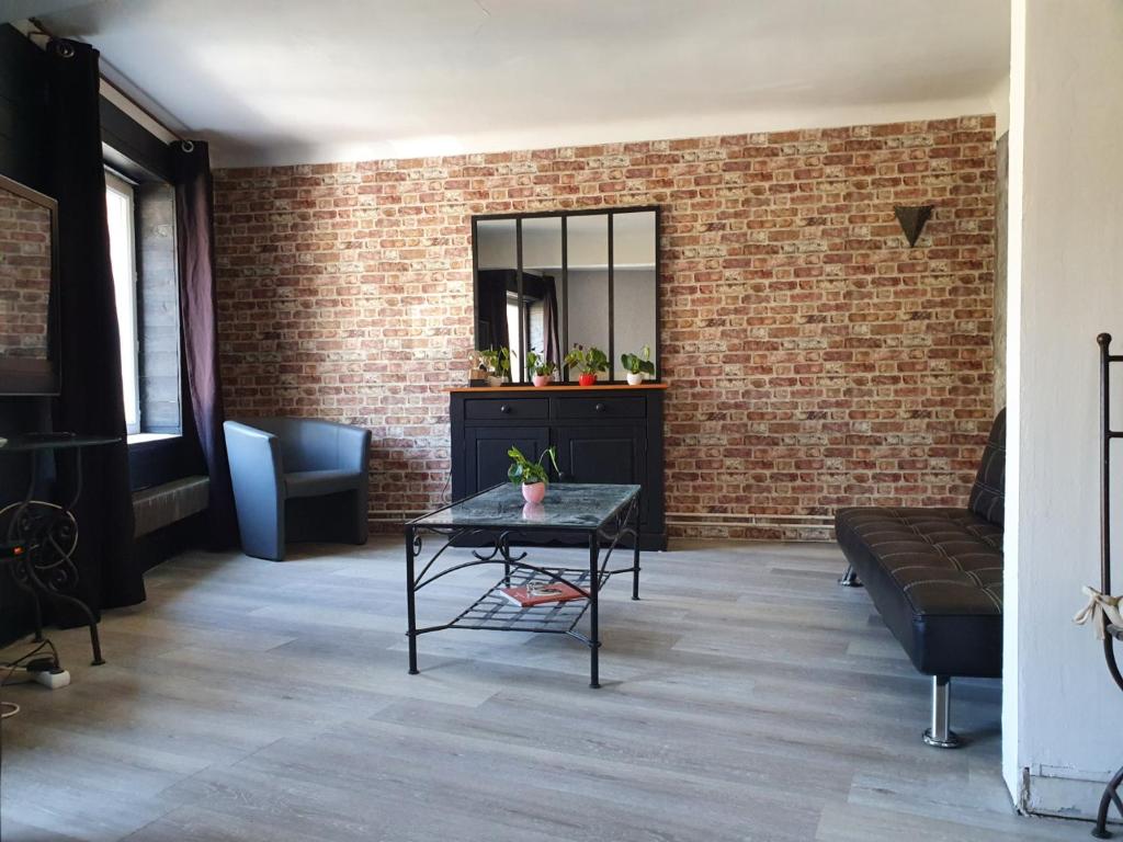 a living room with a table and a brick wall at Maison-Gite métropole Nancy in Vandoeuvre-lès-Nancy