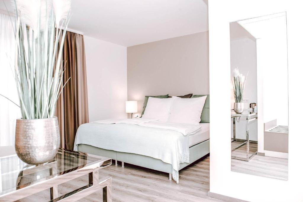 a white bedroom with a bed and a mirror at Concorde Business Boutique Hotel in Bad Soden am Taunus