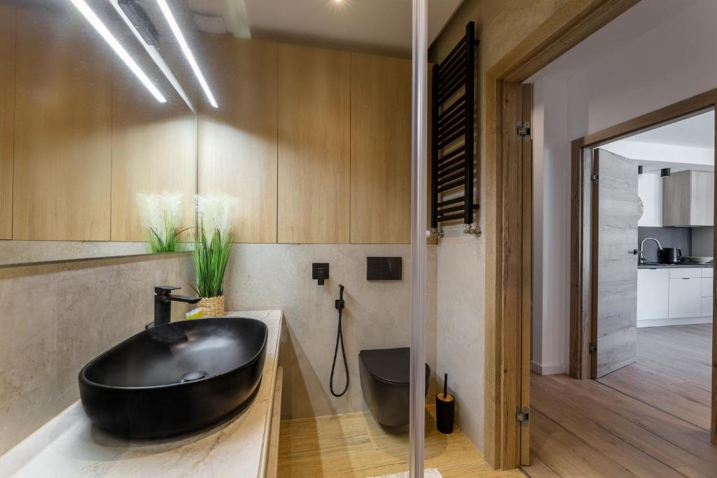 Modern bathroom featuring matte black sink and toilet, wood cabinetry, green plant accent