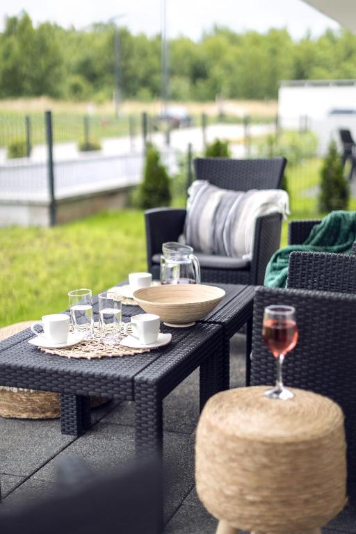 Outdoor patio seating with woven chairs, coffee setup on black table, rosé in foreground