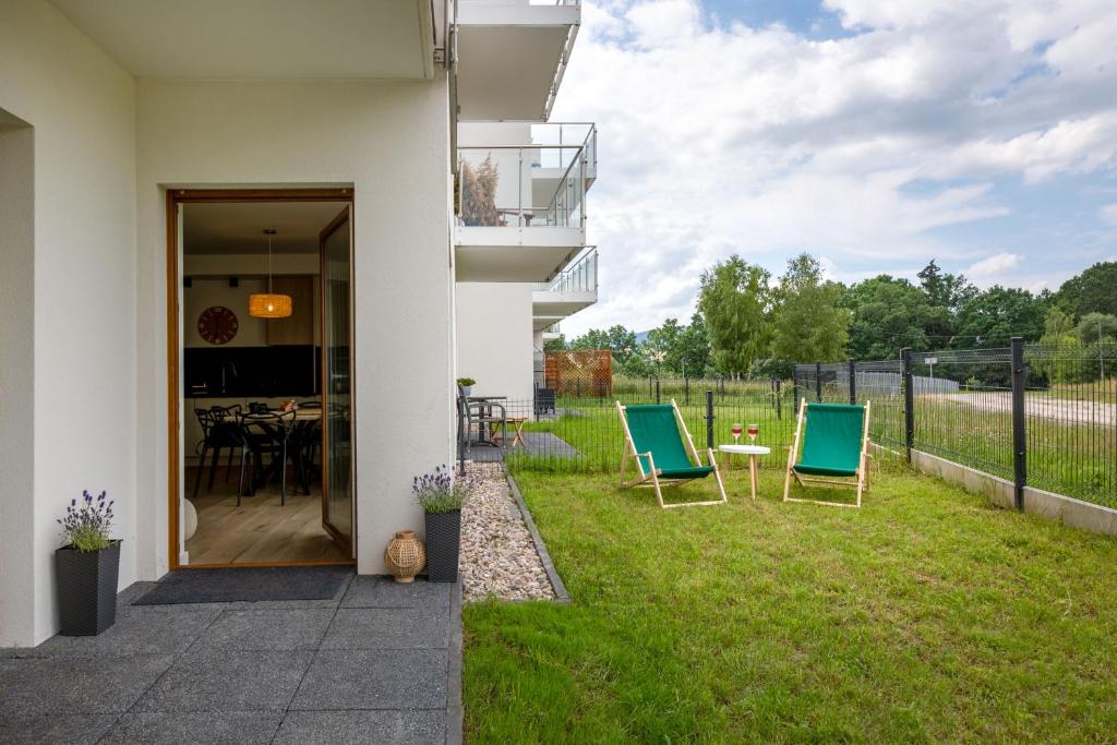 Ground-floor patio opening to apartment, two green deck chairs and small table with drinks.