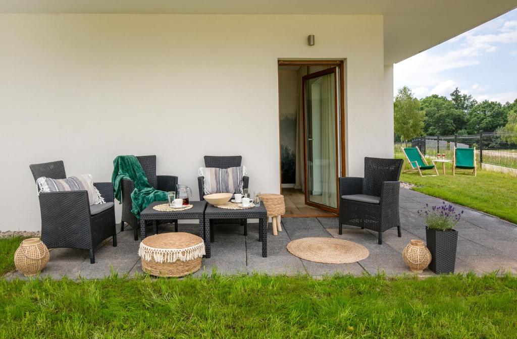 Patio seating with black wicker chairs, coffee table set for drinks, green deck chairs visible beyond.