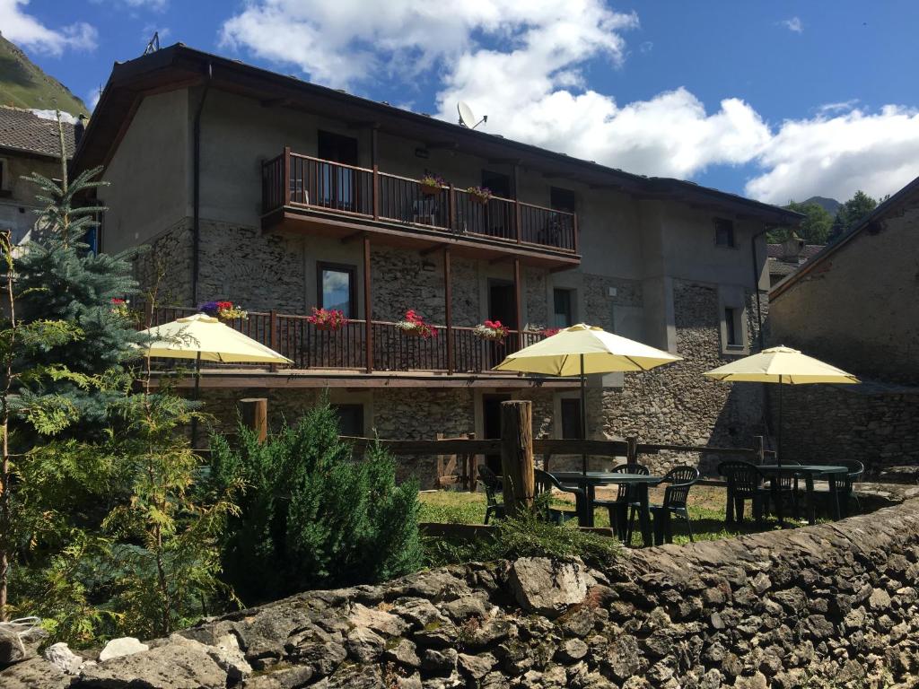 a building with tables and umbrellas in front of it at Il Nido delle Rondini Balboutet in Usseaux