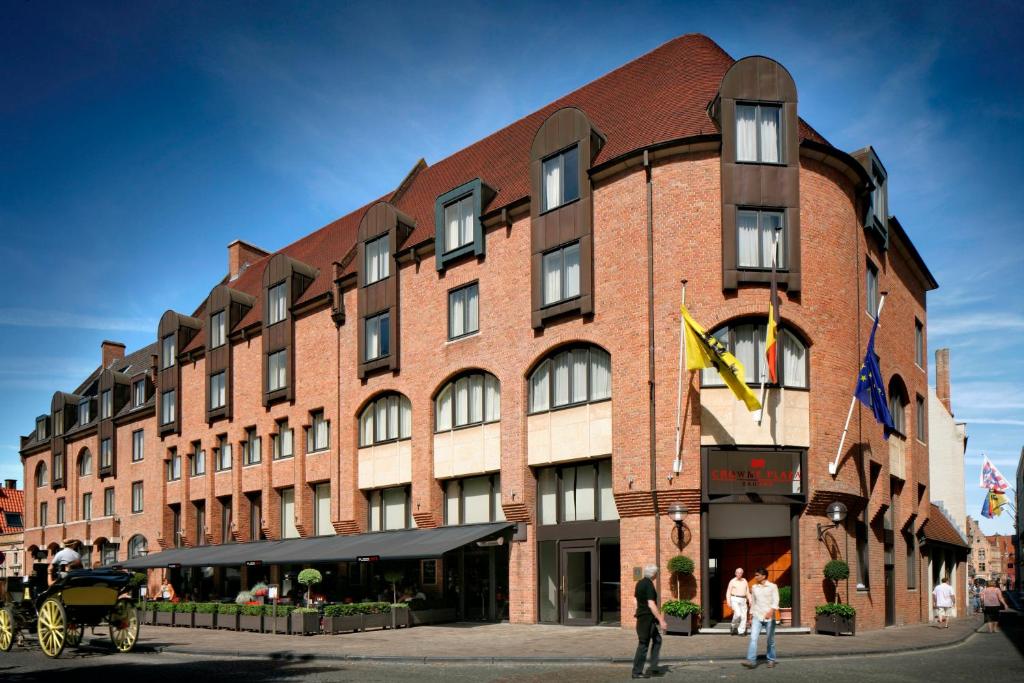 ein großes Backsteingebäude mit Menschen, die draußen stehen in der Unterkunft Crowne Plaza Hotel Brugge, an IHG Hotel in Brügge