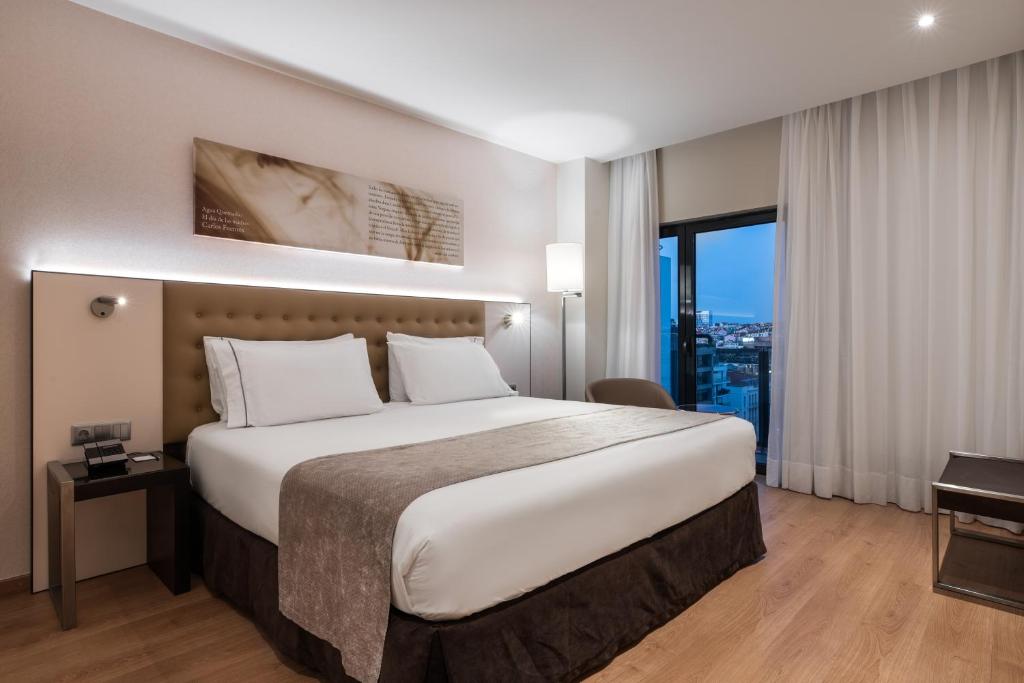 a bedroom with a large bed and a large window at Eurostars Das Letras in Lisbon