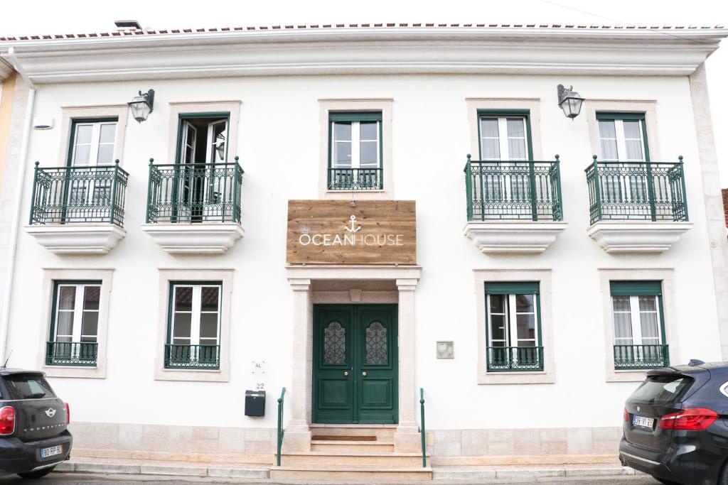 biały budynek z zielonymi drzwiami i balkonami w obiekcie THE OCEAN HOUSE - Baleal w mieście Ferrel