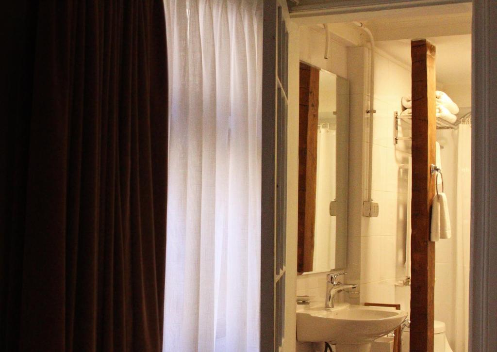 a bathroom with a white shower curtain and a sink at Hotel Boutique Casa Conde in Santiago