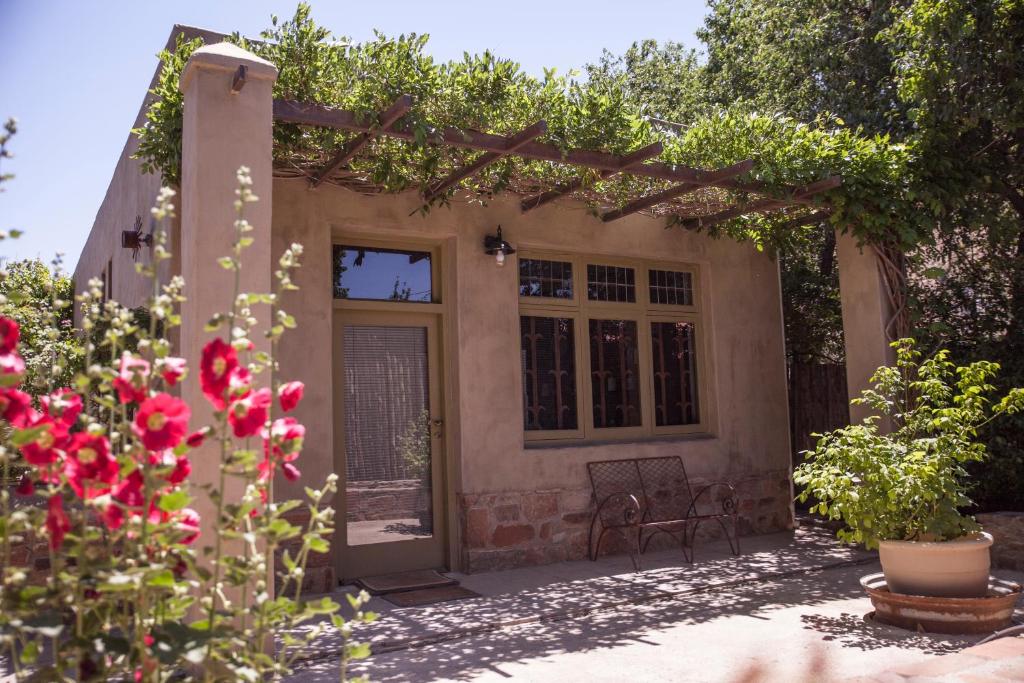 a home with a pergola and red flowers at The Onion Cottage in Nieu-Bethesda