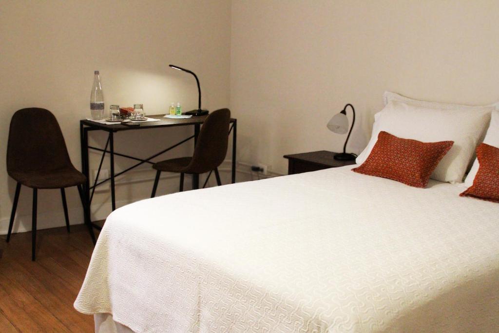 a bedroom with a white bed and a table and chairs at Hotel Boutique Casa Conde in Santiago