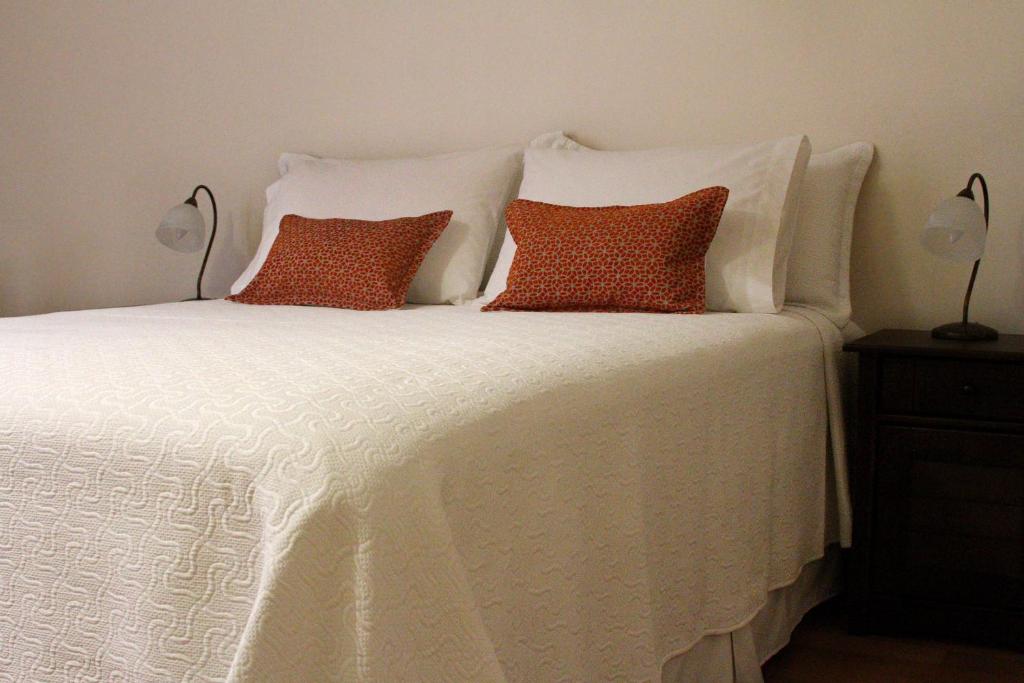 a white bed with two pillows and two lamps at Hotel Boutique Casa Conde in Santiago