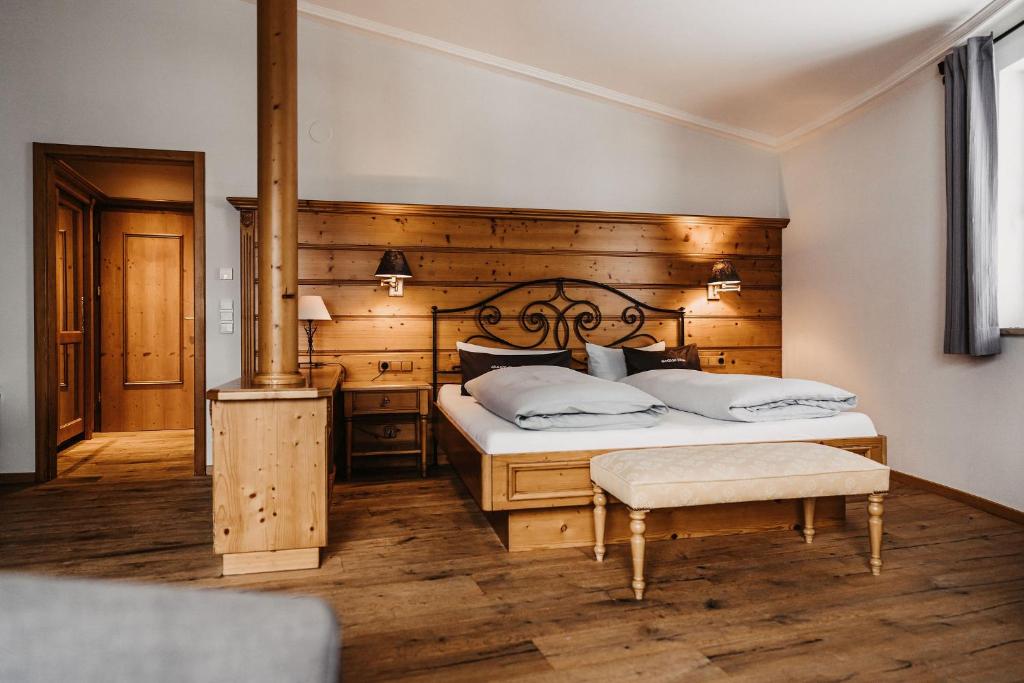 a bedroom with a large bed with a wooden wall at Verwöhn-Wellnesshotel Walserhof in Hirschegg