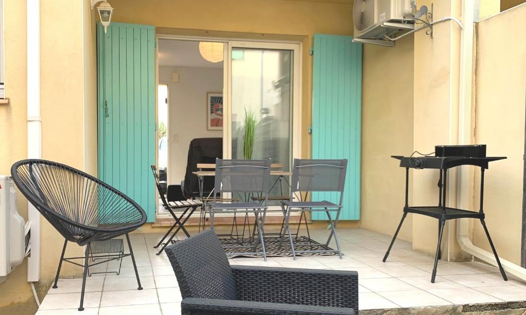 a patio with chairs and a table and a piano at Maison T4 -Jardin+ Parking+ Clim -Proche Remparts in Aigues-Mortes