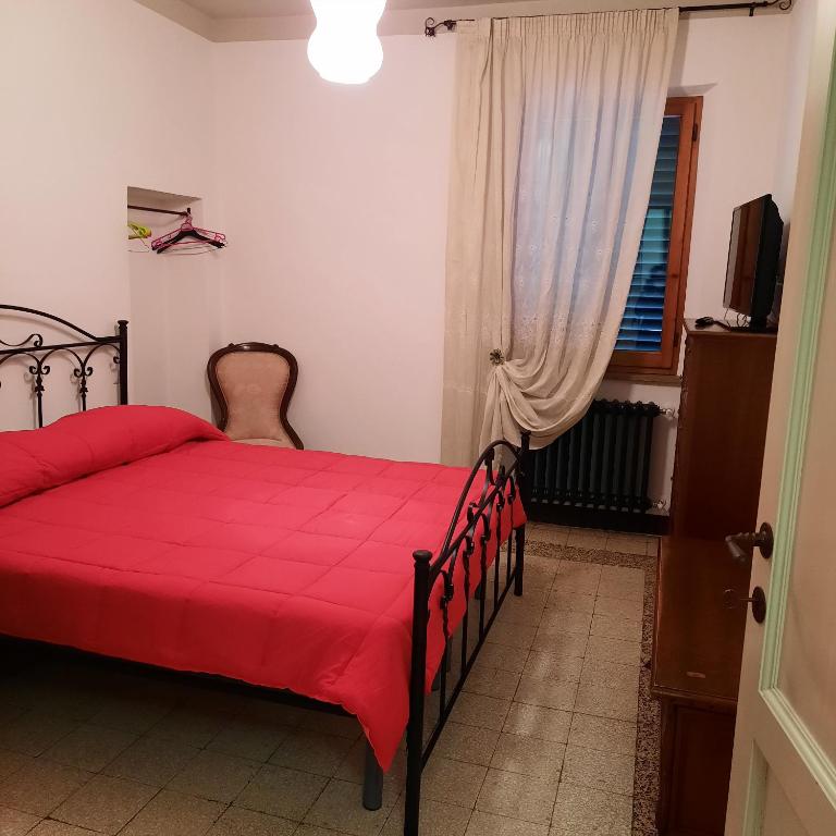 1 dormitorio con cama roja y ventana en NONNA MARI, en Montepulciano