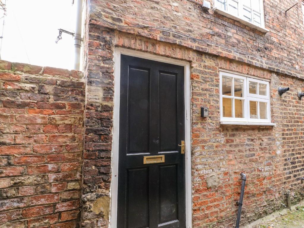 a black door on the side of a brick building at Ickle Pickle Cottage in Thirsk