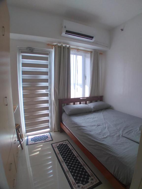 ein Schlafzimmer mit einem großen Bett und einem Fenster in der Unterkunft SM South Residences, 1 bedroom with balcony. in Manila