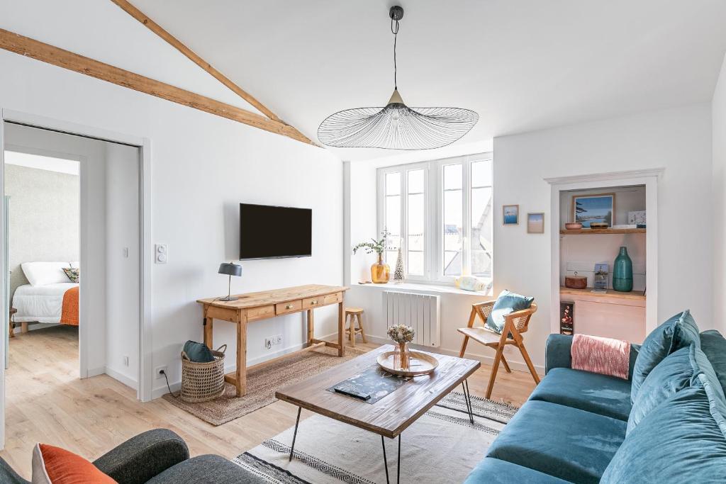 een woonkamer met een blauwe bank en een tafel bij Sieck - Joli Appartement Vue mer in Carantec