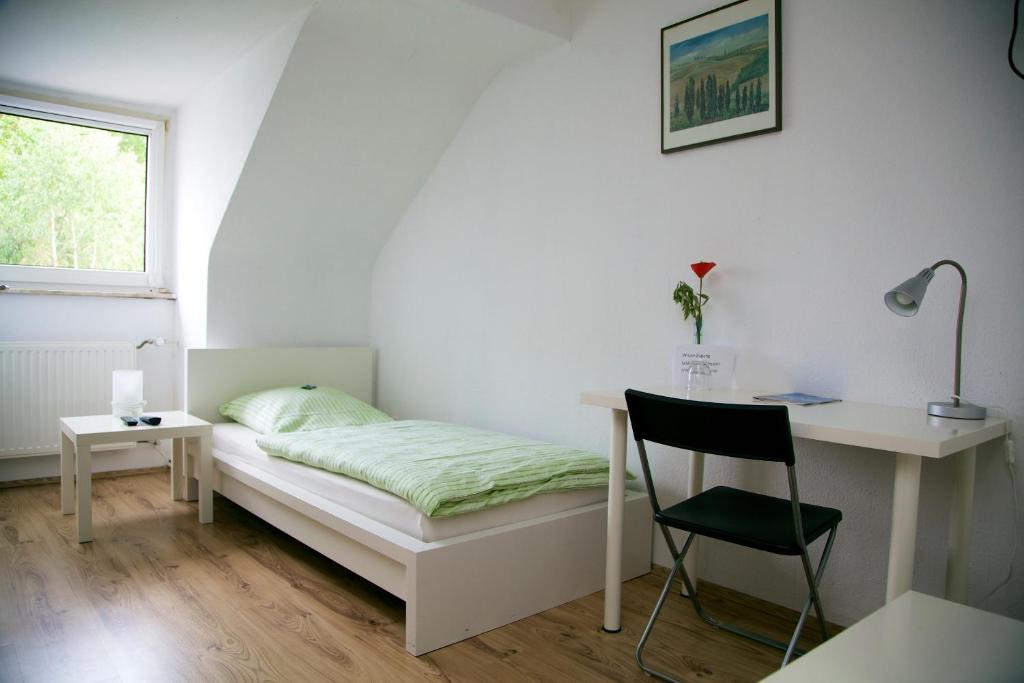 a bedroom with a bed and a desk and a chair at Hotel Hoffmann in Essen