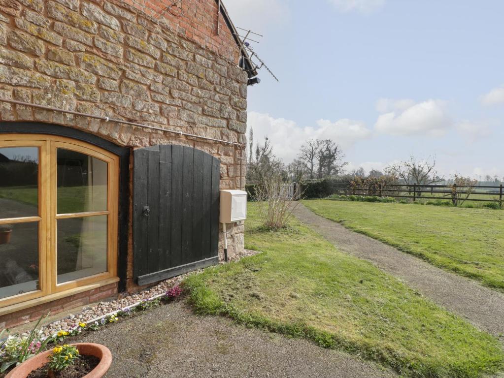 a brick building with a wooden door and a yard at Lower Venn Granary Apartment 1 in Wellington