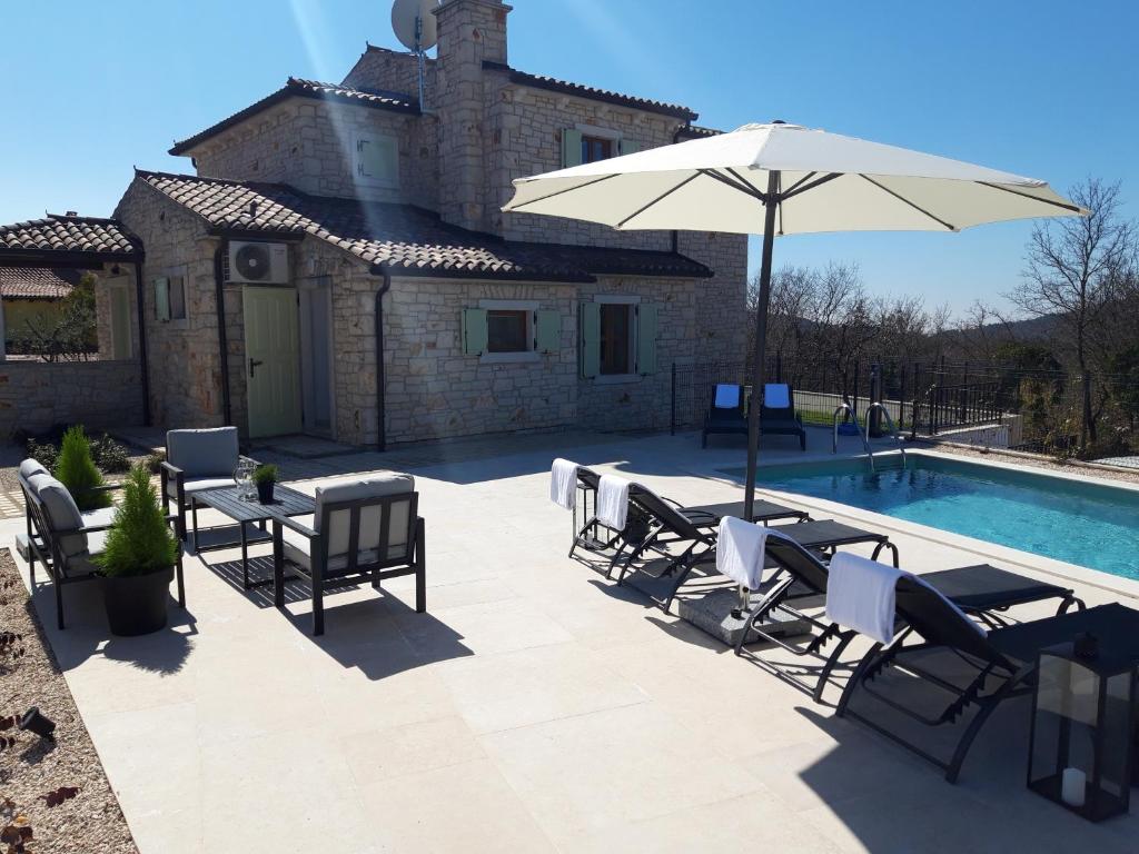 eine Terrasse mit einem Sonnenschirm und Stühlen sowie einem Pool in der Unterkunft Villa Luksa in Grožnjan