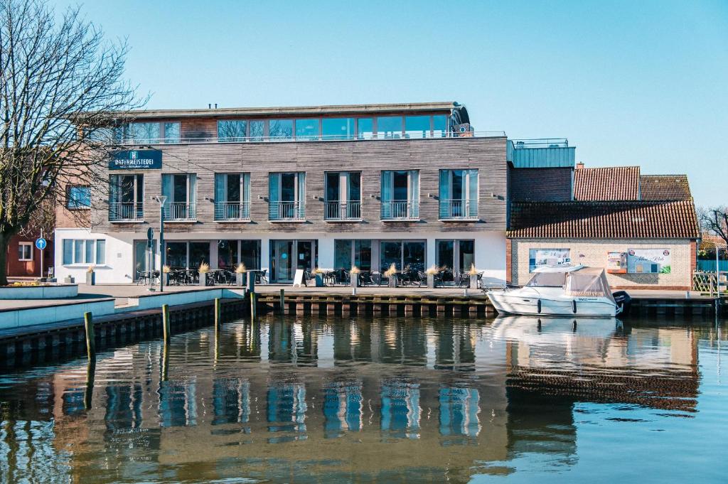 - un bâtiment à côté d'une rivière avec un bateau dans l'établissement Hafenmeisterei, à Steinhude