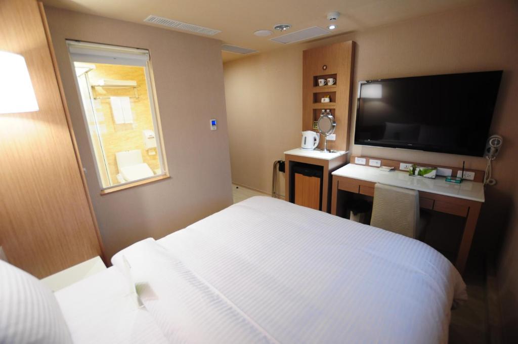 a hotel room with a bed and a flat screen tv at Kindness Hotel - Tainan Chihkan Tower in Tainan