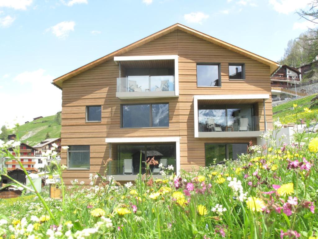 ein Haus auf einem Hügel mit einem Blumenfeld in der Unterkunft Sera Lodge in Grächen